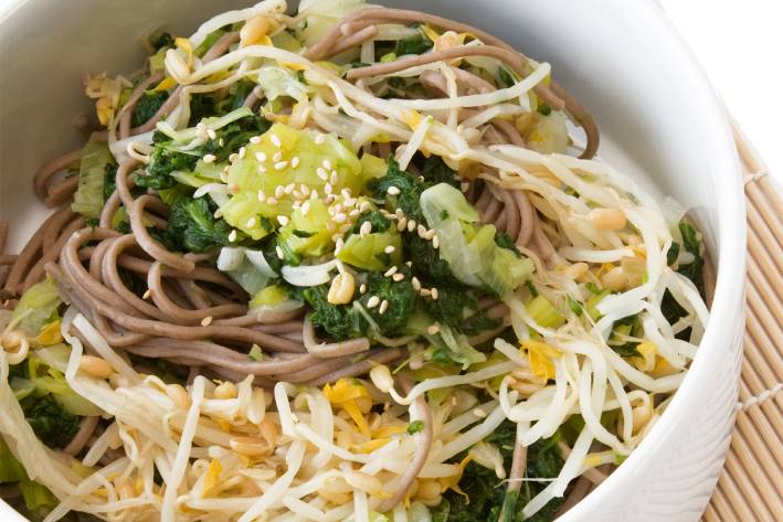 a bowl of soba noodles and leafy greens
