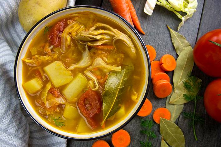 a hot bowl of soup with cabbage, potatoes, and other vegetables