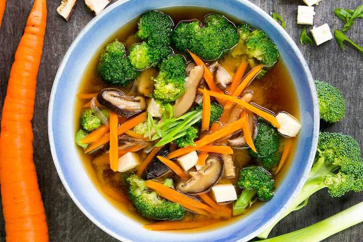 Bowl of miso soup with broccoli, carrots, and shiitake mushrooms 