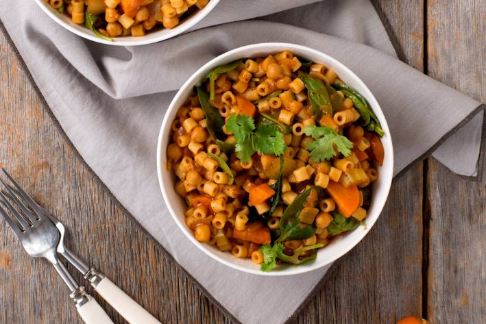 Spicy Ditalini and Chickpea Stew in a white bowl on a wooden table.