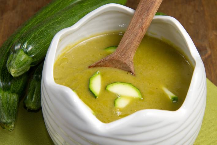 a bowl of creamy soup with sliced zucchini