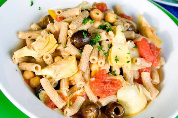 a plate of penne with olives and artichokes