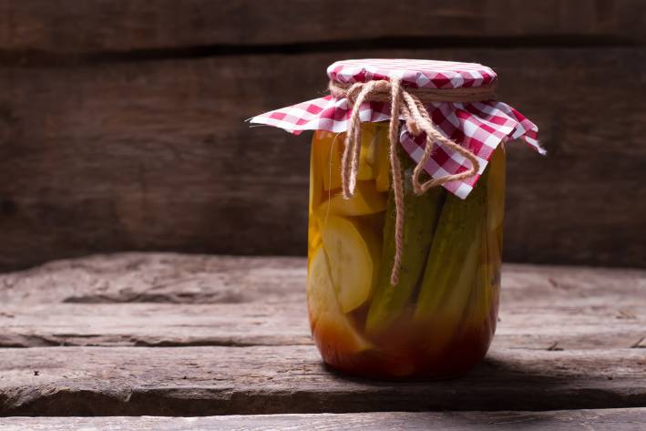 A jar of pickled zucchini on a rustic farm table.