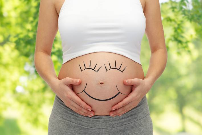a pregnant woman with a smiley face drawn on her bump