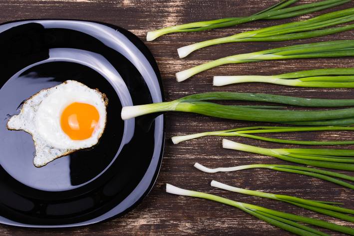 a fried egg and chives laid out to resemble an egg being fertilized