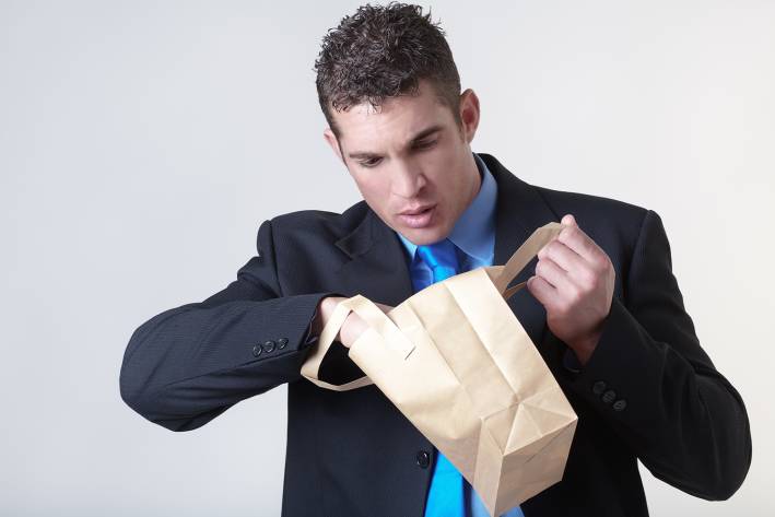 A guy looking in his brown bag lunch at the office
