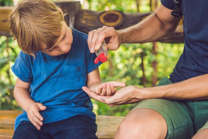 father applying hand sanitizer to toddler son's palm