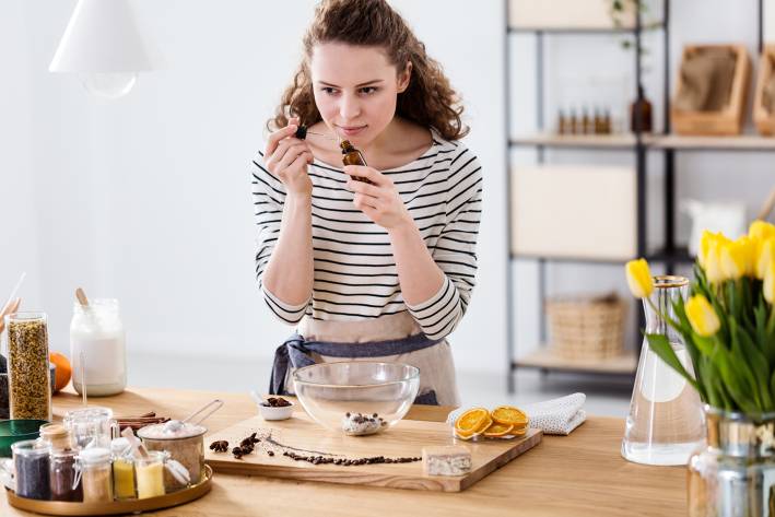 a woman smelling essential oils and citrus peels in her kitchen
