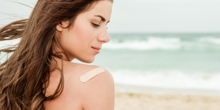 A woman on the beach with a bandage on her shoulder