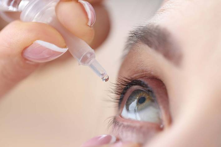 a woman using an eye-dropper of artificial tears