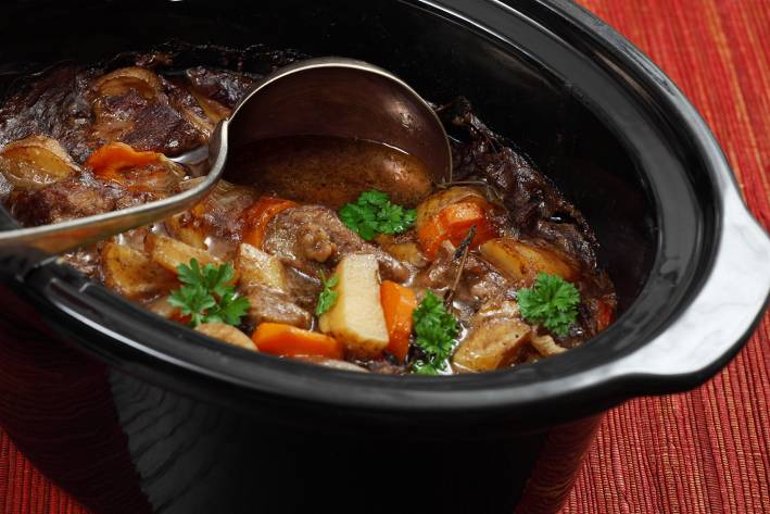 A pot full of hearty beef stew with carrots and potatoes