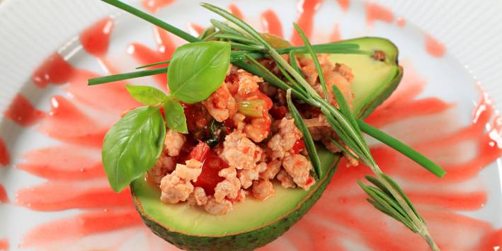Baked avocado halved and stuffed with red rice salsa