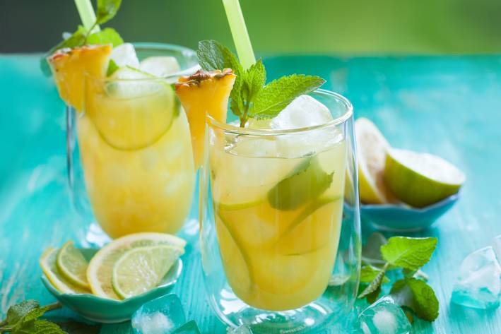 two glasses of pineapple citrus juice with a leafy green garnish