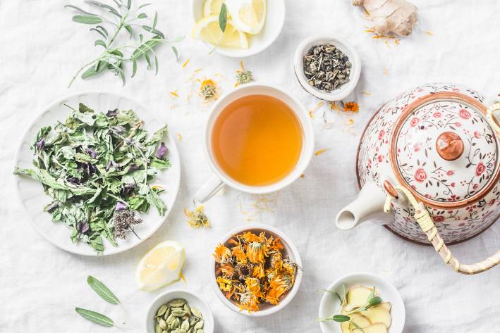 a cup of tea, a teapot, and detoxifying herbs