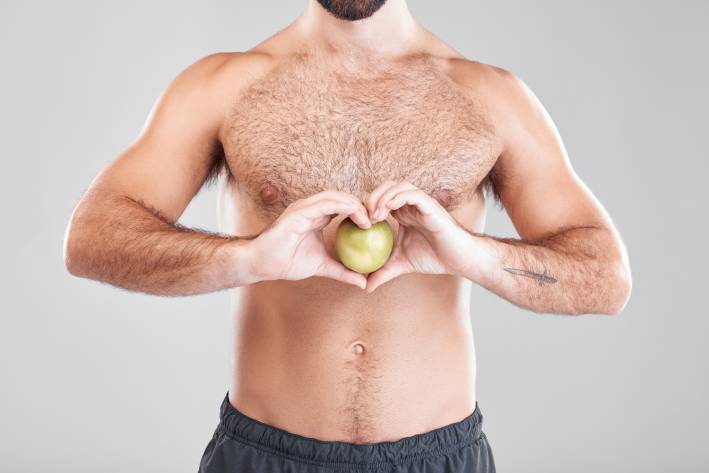 a healthy bare-chested man holding an apple