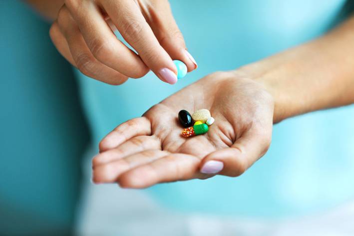 a woman with a few colorful vitamin capsules in her hand