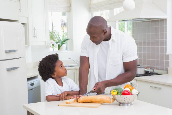 A father and son cooking with healthy foods in the kitchen.