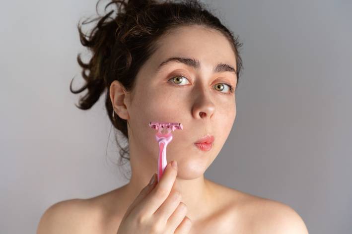 a young woman shaving to remove excess facial hair growth