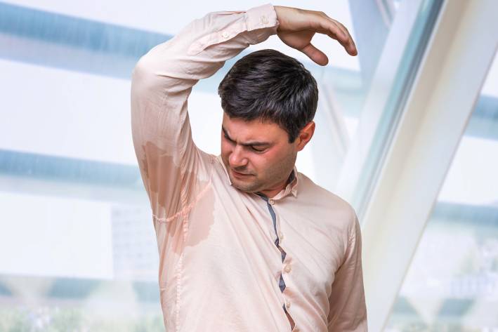 a man sweating heavily through his dress shirt