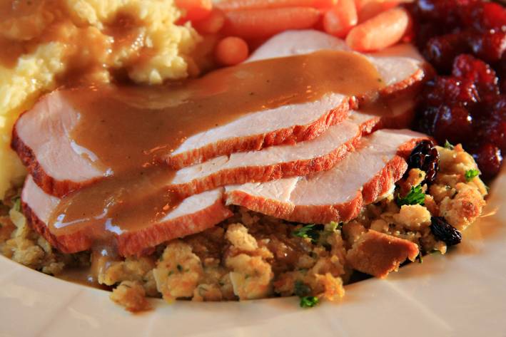 a plate of traditional turkey dinner with stuffing and gravy