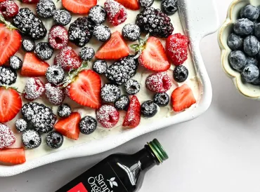 berries on tiramisu with powdered sugar on them also bottle of vanilla extract
