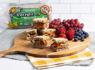sandwich cut up on plate with fruit and bread behind it
