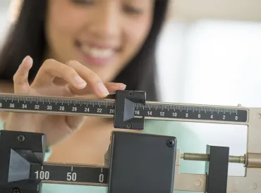 a woman weighing herself with a doctor's scale