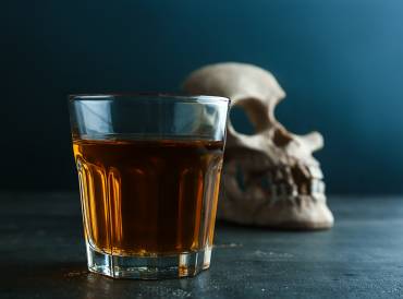 Glass of whiskey with skull on table