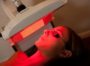 a woman having red light therapy applied to her face