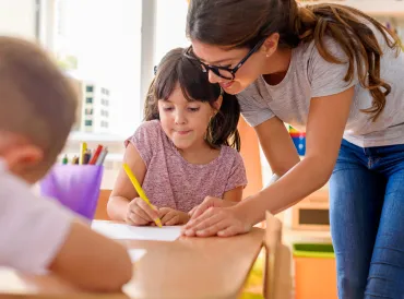 a girl getting help from her teacher in class
