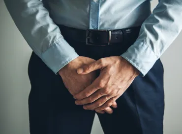 a man patiently holding his crotch