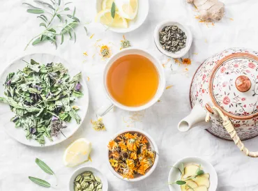 a cup of tea, a teapot, and detoxifying herbs