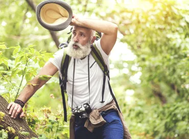 a healthy-looking man feeling exhausted on a hike in the woods