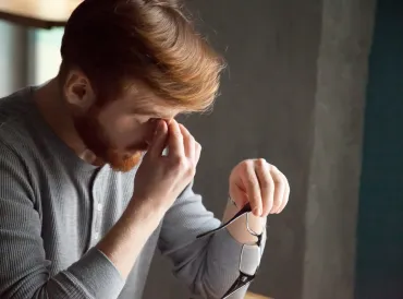 Tired red haired man massaging nose feeling fatigue from work.
