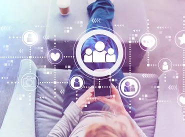 Man using a cell phone with social media icons illustrated above it.