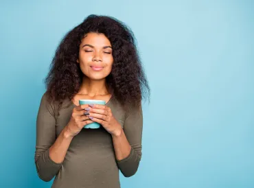 a woman with a calmly glowing smile holding a mug of tea