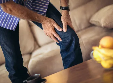 a middle-aged man grabbing his bad knee in pain
