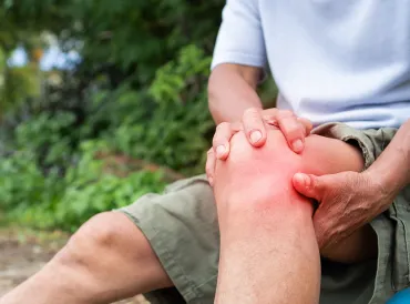 an older hiker grabbing his knee in pain