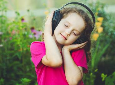 a little girl bopping to her headphones in a field of flowers
