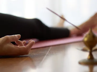 a woman in the yogic corpse pose with incense