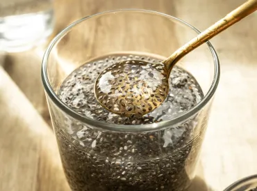 a glass of chia seeds in water, soaking into a gel that collects on a spoon