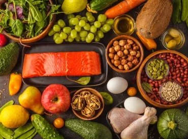 Elements of a Paleo diet, including fruits, salmon, poultry, nuts, eggs.