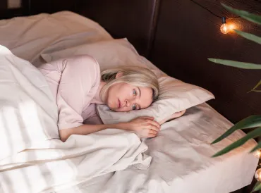A blonde woman in early middle-age lying awake at night. 