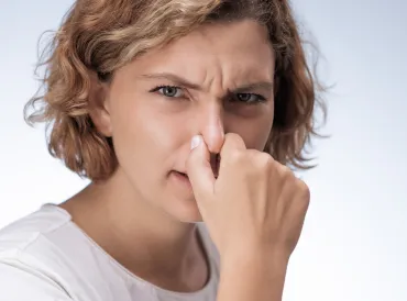 Woman holding her nose.