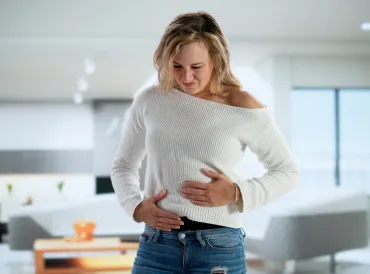 Woman holding both sides of her guts.
