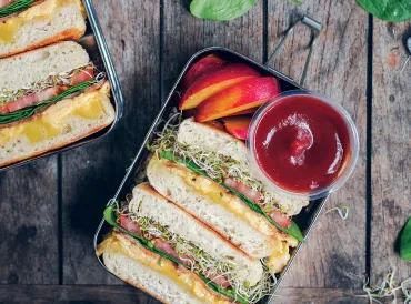 an egg sandwich and plum slices in a bento box
