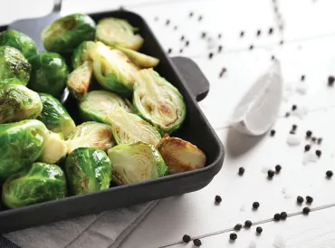 Roasted Brussels Sprouts in a black baking dish on a white table.