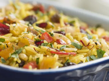 Dish of hot brown rice cereal with chunks of dried fruit