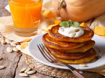 a stack of pumpkin pancakes and a glass of orange juice