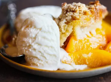 a bowl of warm peach cobbler and a scoop of vanilla ice cream